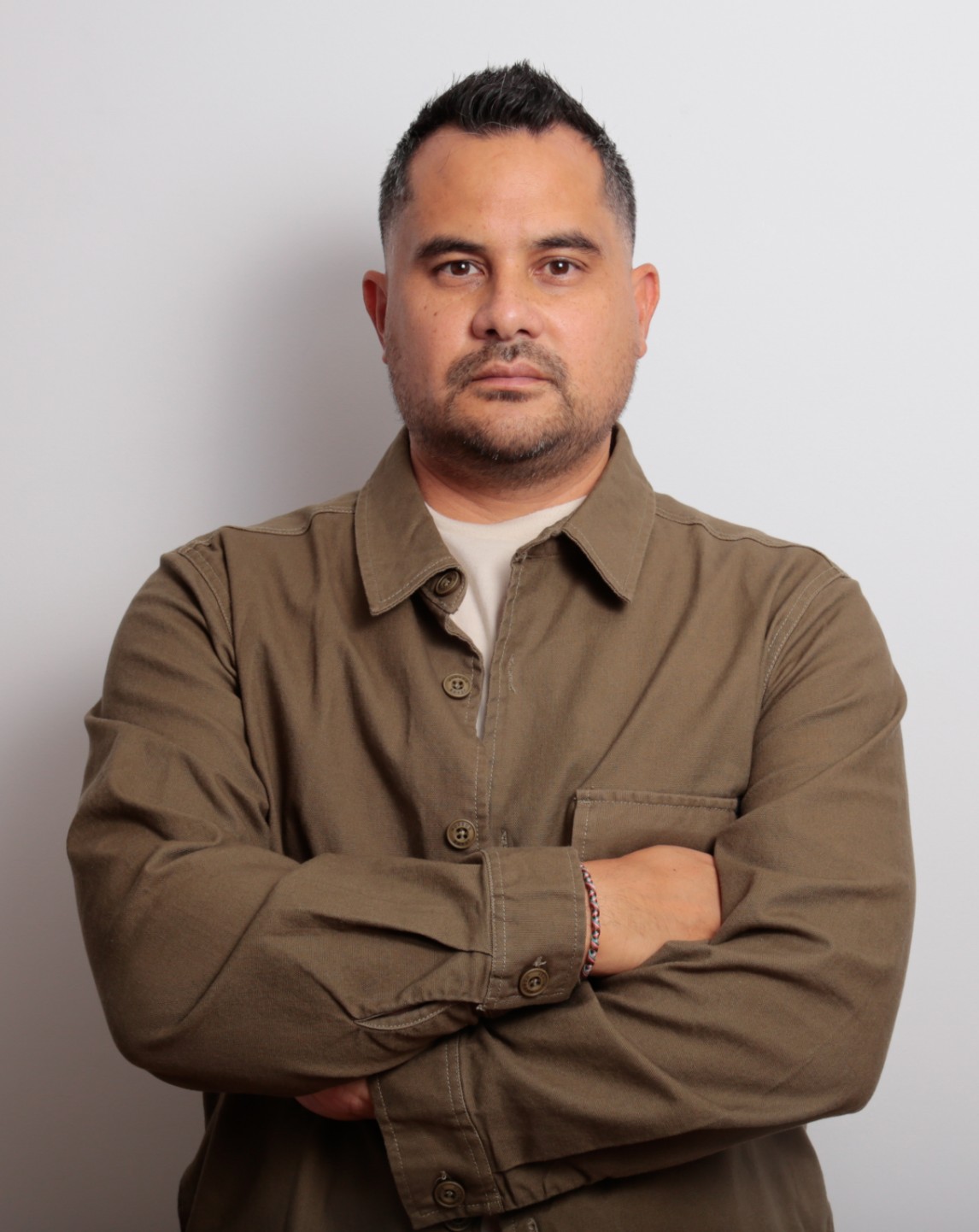 American portrait photo of Yang with his arms crossed wearing a khaki jacket